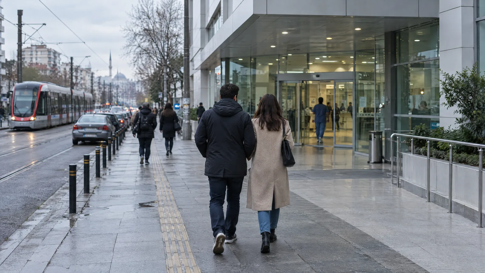 İstanbul'da tramvay hattının yanındaki bir hastanenin girişine yürüyen çift, arkadan